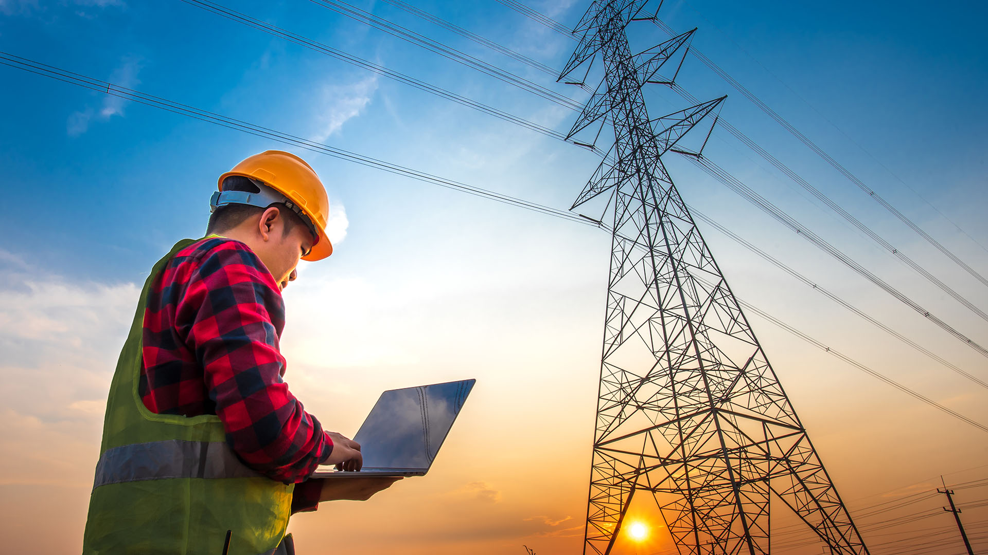 Male electrical engineer using a notebook computer notebook computer standing at a power station to see the planning work by producing electrical energy at high voltage electrodes